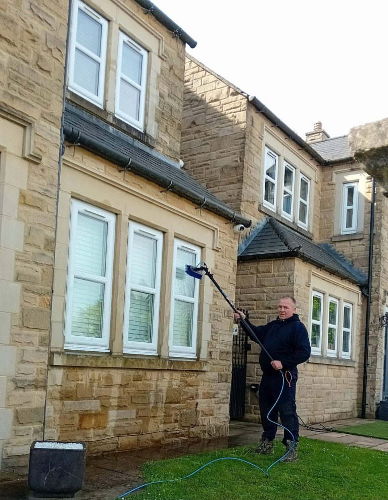 Window cleaning a stone house with a water-fed pole